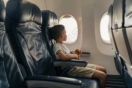 带着玩具的小孩坐在飞机座位上图片