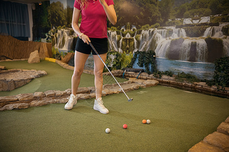 一个在室内打小型高尔夫球的年轻女子图片