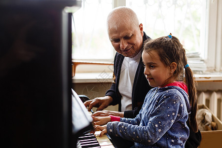 教钢琴爷爷教女孩弹钢琴 开心地弹琴 男性 假期 享受背景