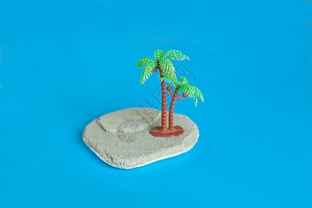 海滩上最微小的塑胶玩具  蓝纸石头上的玩具棕榈树图片