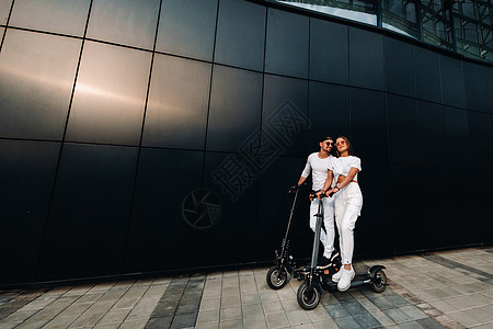 一个女孩和一个男人在城市周围骑着电动摩托车行走 一对情侣爱着摩托车 驾驶 技术图片