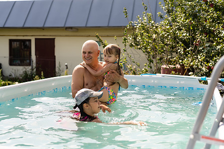 一个快乐的祖父的肖像 孙子在游泳池里 假期图片