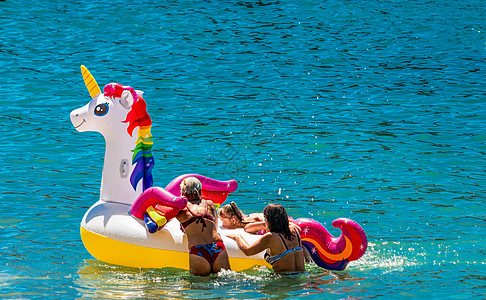 家庭在蓝色的大海上玩白色独角兽 日落假期旅行度假背景与有趣的独角兽玩具浮动标题作为浪漫的家庭背景 夏季家庭旅游目的地图片
