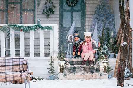 快乐的小孩们坐在圣诞礼堂门廊上 户外装饰房子 孩子 冬天图片