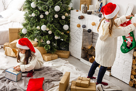 2个小女孩在圣诞节早晨 分享一个惊喜 手图片