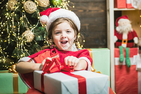 兴奋可爱的孩子打开圣诞礼物 拿着一个红色礼物盒的圣诞节孩子女孩图片