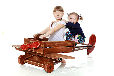 两个姐妹在木制飞机上玩耍 动机 翅膀 童年 头盔图片