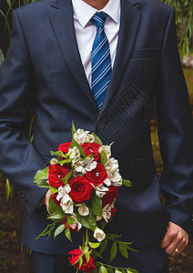 新郎穿着白衬衫 蓝西装和领带 握着白红玫瑰花新娘的结婚花束子图片