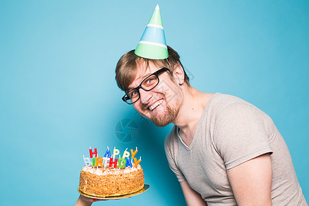 疯狂的 滑稽的 正人君子和快乐的生日蛋糕 站在蓝色背景上 笑柄和节日问候的概念图片