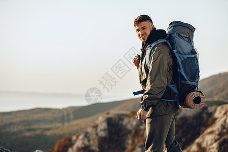 年轻的天主教男子旅行者 在山上徒步旅行 背着大背包在山上远足 悬崖 运动图片