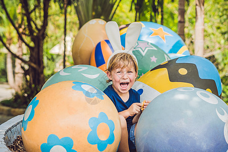 可爱的小男孩 长着兔耳朵 在户外玩传统的复活节彩蛋 庆祝复活节假期 蹒跚学步的发现 五颜六色的鸡蛋 花 姐姐图片