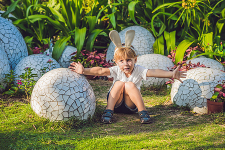 可爱的小男孩 长着兔耳朵 在户外玩传统的复活节彩蛋 庆祝复活节假期 蹒跚学步的发现 五颜六色的鸡蛋 戏服 孩子们图片