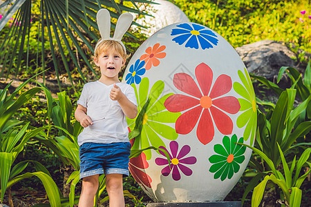 可爱的小男孩 长着兔耳朵 在户外玩传统的复活节彩蛋 庆祝复活节假期 蹒跚学步的发现 五颜六色的鸡蛋 打猎 童年背景图片