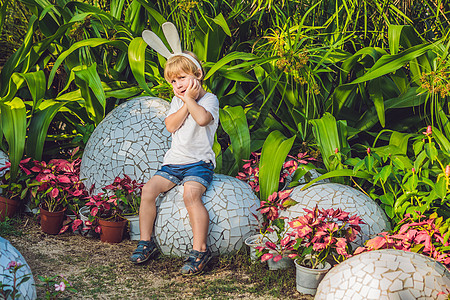 可爱的小男孩 长着兔耳朵 在户外玩传统的复活节彩蛋 庆祝复活节假期 蹒跚学步的发现 五颜六色的鸡蛋 春天 兔子图片