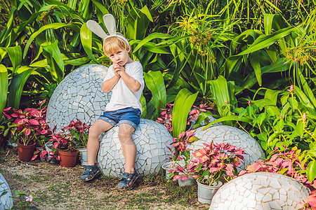可爱的小男孩 长着兔耳朵 在户外玩传统的复活节彩蛋 庆祝复活节假期 蹒跚学步的发现 五颜六色的鸡蛋 兔子 童年图片