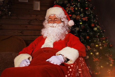 圣诞老人在家壁炉附近坐着舒服的椅子休息时 享受舒适的生活 节日 戏服图片