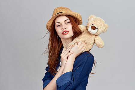 戴着帽子的开心女人 带着泰迪熊礼物玩具 脸图片