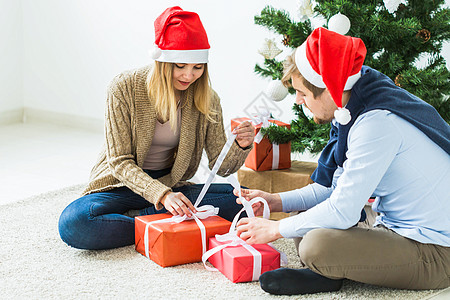 假日 关系和节日概念   圣诞树前的一对夫妇开放礼物 成人 冬天图片