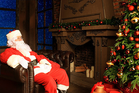 圣诞老人在家壁炉附近坐着舒服的椅子休息时 享受舒适的生活 节日 男人图片