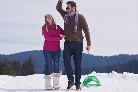 圣诞节情侣快乐的年轻情侣在冬季假期 新秀上玩得开心 自然 雪橇背景