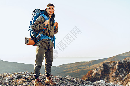 年轻的天主教男子旅行者 在山上徒步旅行 背着大背包在山上远足 日出 冒险图片