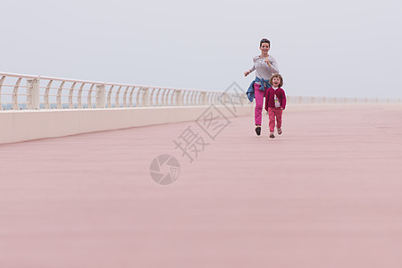 小女孩奔跑母亲和可爱的小女孩 在海边的赛道上 美丽 美丽的背景