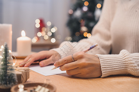 新年圣诞节概念的目标计划要做和愿望清单 女孩写在笔记本上 寒假圣诞节 女人手拿着笔在家里的记事本上 圣诞装饰 礼品盒 包装 希望图片