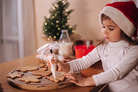 圣诞老人帽子的小女孩在家里装饰姜饼 圣诞节和新年传统概念 圣诞面包店 假期愉快 女性 生的图片