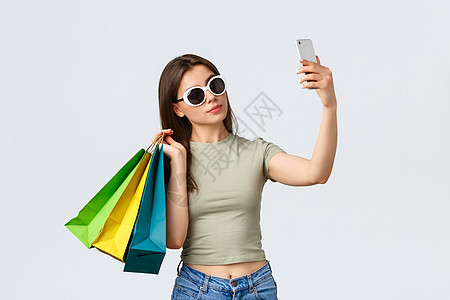 购物中心 生活方式 旅游和时尚概念 戴着太阳镜 带着购物袋自拍 在最喜欢的商店买东西的快乐迷人女游客 银行 钱图片