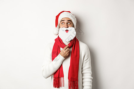 享受新年 戴着白色圣诞老人胡子面罩 戴红色帽子 工作室背景的有趣的男人 Y L 图片