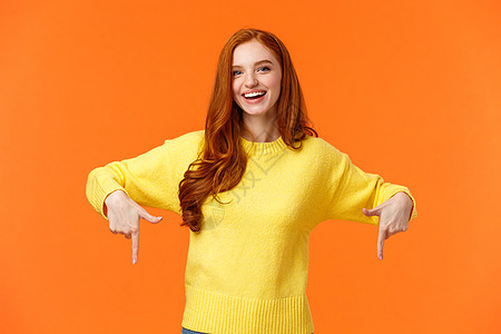 穿着黄色毛衣的红发女学生 邀请退校活动 推荐自豪感 克里斯马斯销售 节日宣传 低指和微笑 橙色背景等 都令人欢欣鼓舞图片