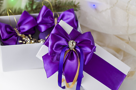 装饰圣诞树一份圣诞礼物 在浅色背景上用冷杉树枝装饰着美丽的蝴蝶结 礼物 喜悦 惊喜 选择性的焦点 圣诞节和新年的概念 帽子 弓背景