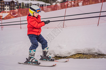 男孩使用训练升降机 儿童在山中滑雪 带安全帽 护目镜和杆的活跃蹒跚学步的孩子 幼儿滑雪比赛 家庭的冬季运动 高山学校的孩子们滑雪图片