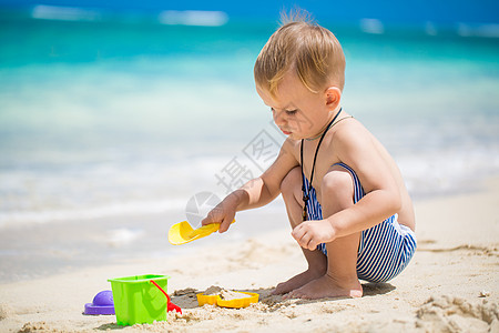 在热带海滩玩沙滩玩具的可爱小男孩 夏天 童年图片