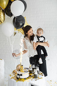 母亲和儿子一起庆祝一岁生日 带着气球笑着笑着 一个糖果棒 糖果条 乐趣图片