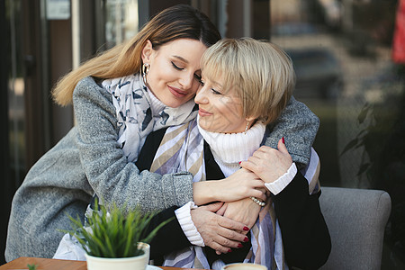 成年女儿在咖啡馆碰面时拥抱和亲吻年老的母亲图片
