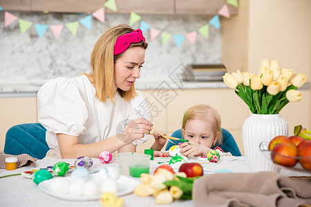 幸福的家庭为复活节做准备 有妈妈画鸡蛋的可爱女孩 家庭活动 团结和爱的概念 妈妈和女儿 创造力 母亲图片