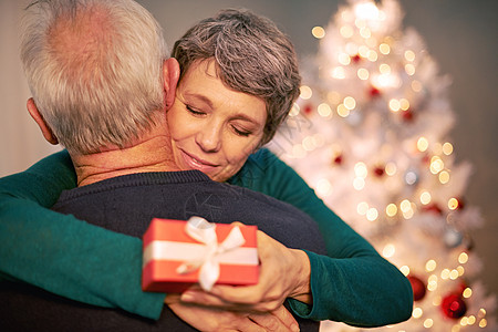 在圣诞节宠爱他的爱人 交换圣诞礼物后 一对幸福的成熟夫妇拥抱的镜头图片
