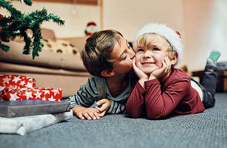 今年的圣诞老人礼物 没有手足之争 拍摄的是一个可爱的小男孩在等待打开他们的圣诞礼物时亲吻他的兄弟图片