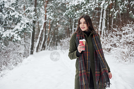 穿着温暖衣服的姑娘喝着咖啡 在冬季森林里散步 Y 我 图片
