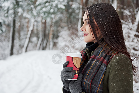 天气天气好 侧面风景 穿着温暖衣服的姑娘喝咖啡在冬季森林散步图片