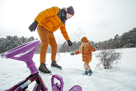 父亲在冬天拉着小儿子上雪橇 孩子们 爬坡道 微笑图片