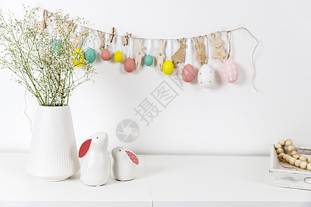 内部的片段 为复活节装饰的儿童房 墙上的塑料鸡蛋花环 桌子上的陶瓷兔子和木制立方体 您的文本的地方 复活节贺卡 雕刻 野兔图片