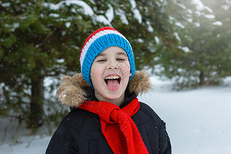 穿冬衣的有趣男孩 红围巾用舌头抓着雪花 行动图片