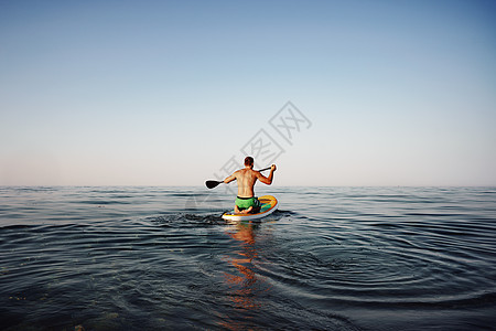 在海中漂浮在船桨上的人的后视镜 海滩 站立 桨板图片