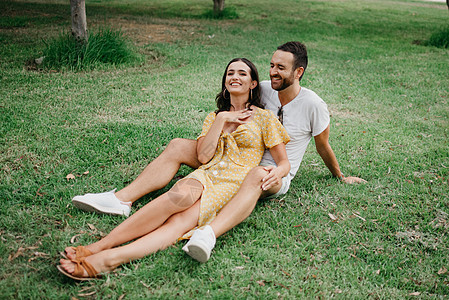 穿黄色裙子的女孩 在草地上坐在她男朋友的两腿之间 街头风 微笑背景图片