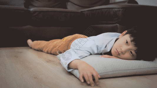 客厅关灯趴在枕头上发呆的小男孩GIF高清图片