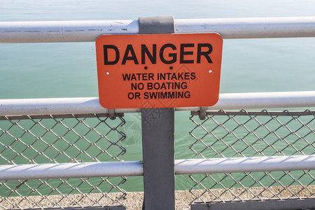 河边栅栏上的橙色警告标志危险水进口不图片