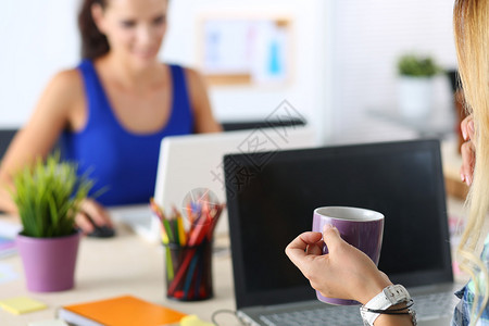 办公室里的两位女设计师喝早茶或咖啡在辛勤工作的一天喝咖啡女员工拿着一杯热饮有创意的人或插画