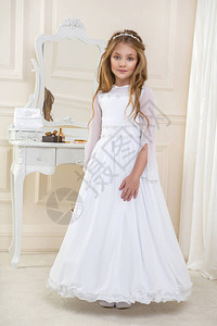 穿着白圣餐礼服的美丽年轻女子模特站在一个图片